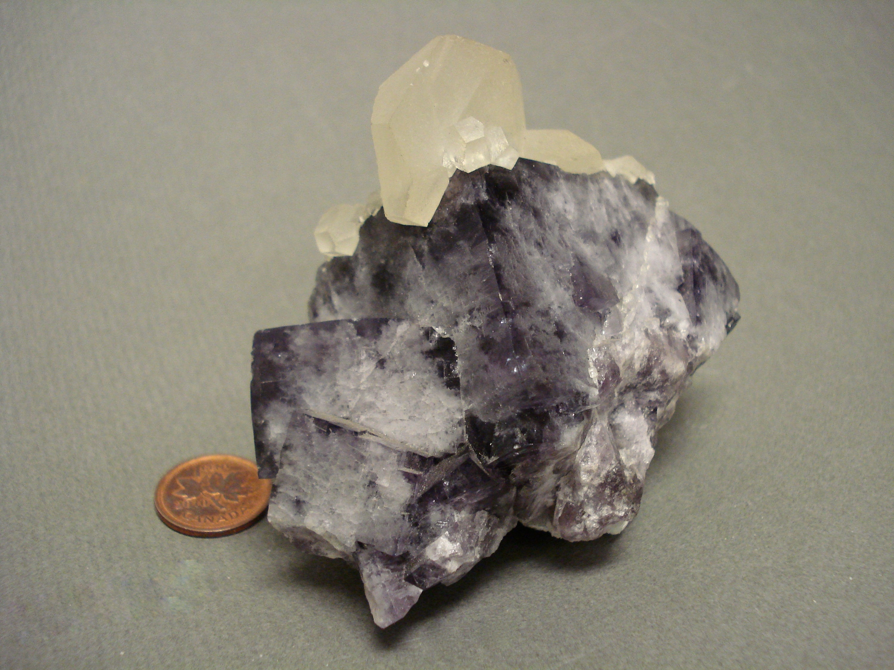 Poker Chip Calcite on Fluorite next to a penny for size comparison