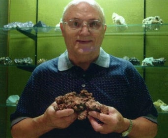 Johann Werner holding mineral in front of case of other minerals