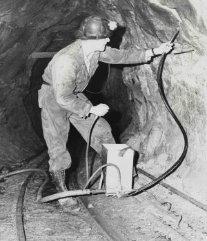 man places detonator into rock wall of mine tunnel