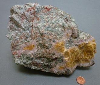 Cancrinite next to a penny for size comparison.