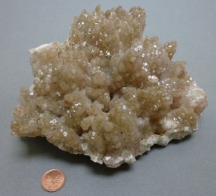 Calcite next to a penny for size comparison.