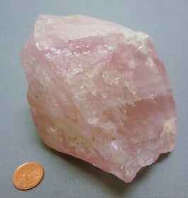 Rose quartz next to a penny for size comparison