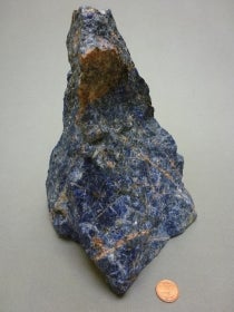 Sodalite next to a penny for size comparison
