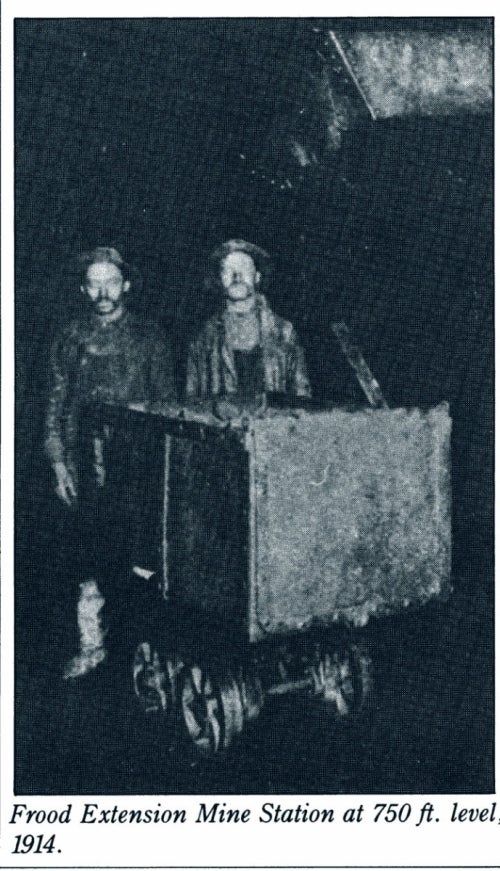 two miners standing with mine cart in dark mine tunnel