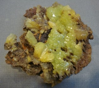 Yellow- green coloured mineral with brown rock or mineral