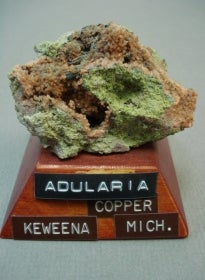 Adularia mineral mounted on a wood base with a label