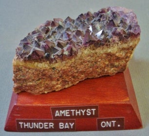 Amethyst mounted on a wood base with a label