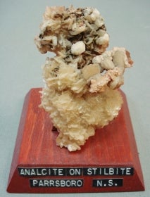 Analcite on stilbite mounted on a wood base with a label