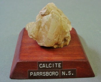 Calcite mounted on a wood base with a label