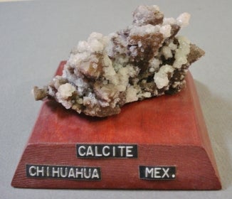 Calcite mounted on a wood base with a label