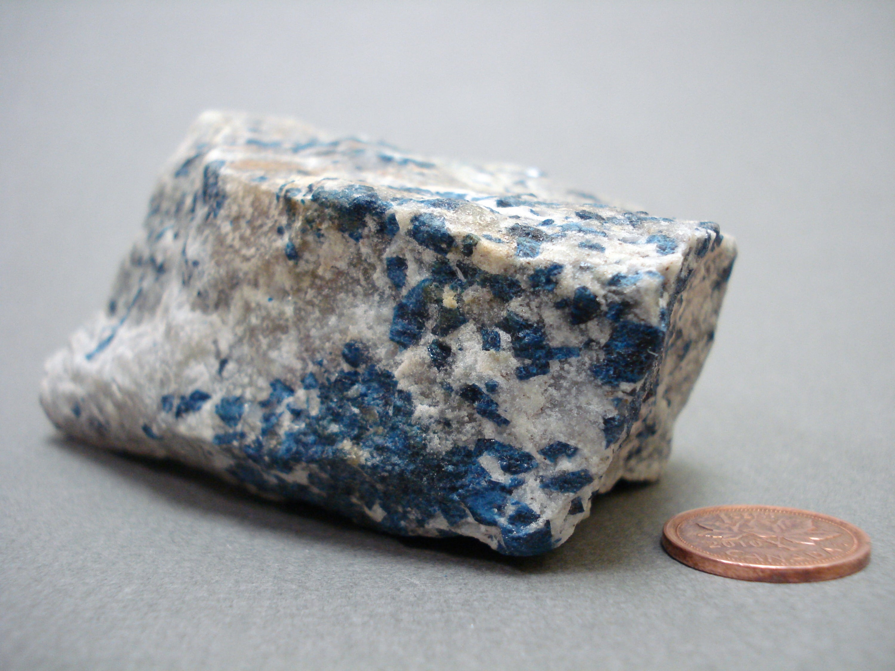 Lazulite next to a penny for size comparison