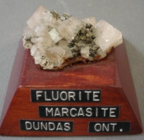 Fluorite on marcasite mounted on a wood base with a label