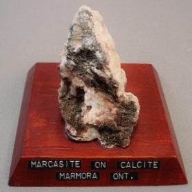 Marcasite on calcite mounted on a wood base with a label
