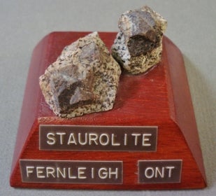 2 pieces of Staurolite mounted on a wood base with a label