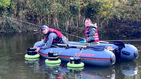 Researchers Stephanie Slowinski and Christina Lam sampling in a storm water pond from a boat.