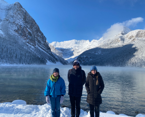 Erin Griffiths, Philippe van Cappellen, Jovana Radosavljevic standing in front of a lake and mountains in Banff, Alberta.