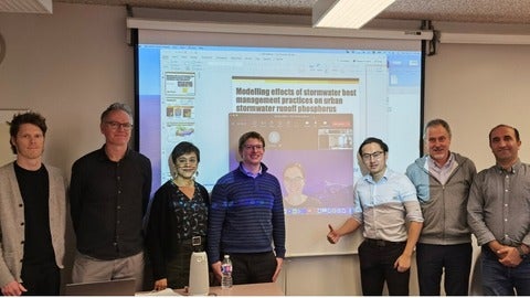 Members of Bowen Zhou's thesis defence committee posing together after the defence: Committee chair, Bruce McVicar, Nandita Bass, Chris Parsons, Bowen Zhou, Philippe Van Cappellen, Fereidoun Rezanezhad, pictured onscreen Elodie Pasteport.
