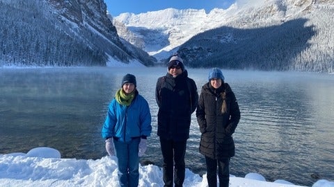 Erin Griffiths, Philippe van Cappellen, Jovana Radosavljevic standing in front of a lake and mountains in Banff, Alberta.