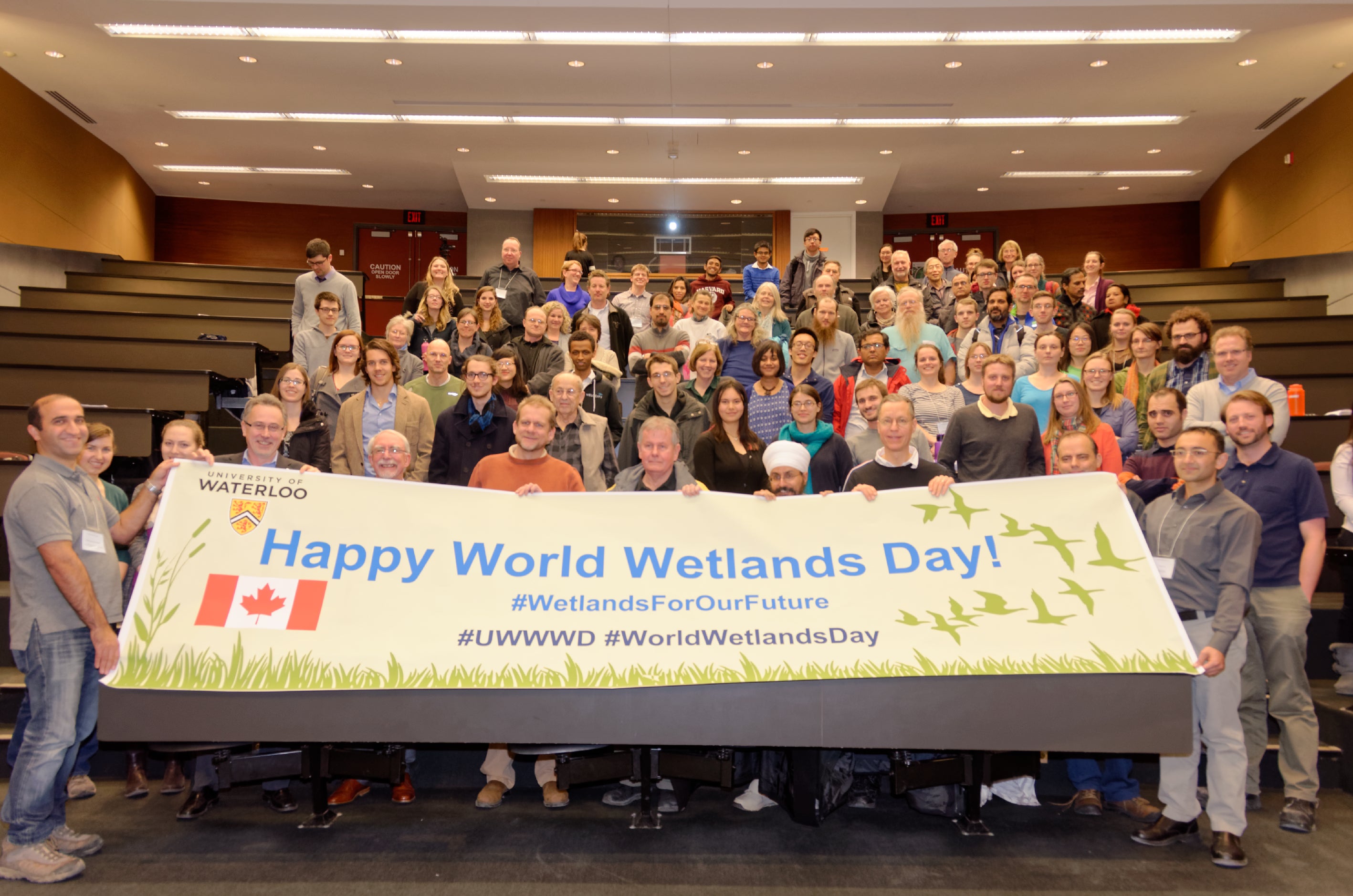 Large group of people holding World Wetlands Day Banner