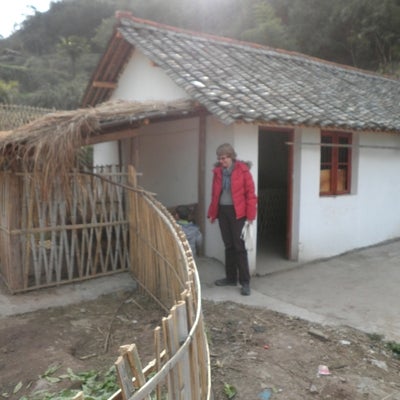 Person in a red coat standing outside a house