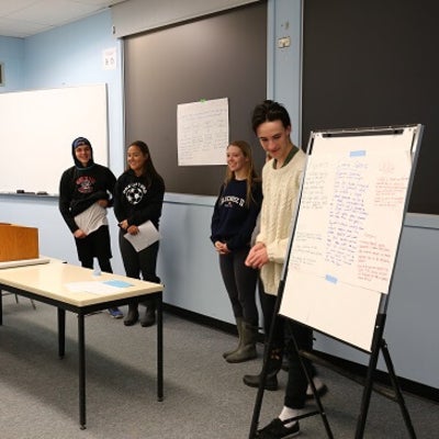 Students presenting their findings with a flip chart in the classroom