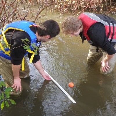 Students holding meter stick above water