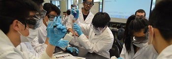 students doing chemical analysis in lab coats and goggles
