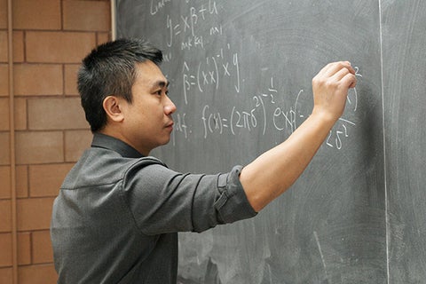 An economics student working on equations on a blackboard