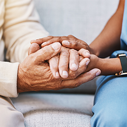 close up of care worker in scrubs holding an elderly person's hands