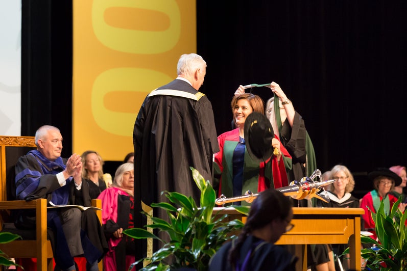 PhD student being hooded on stage at Convocation