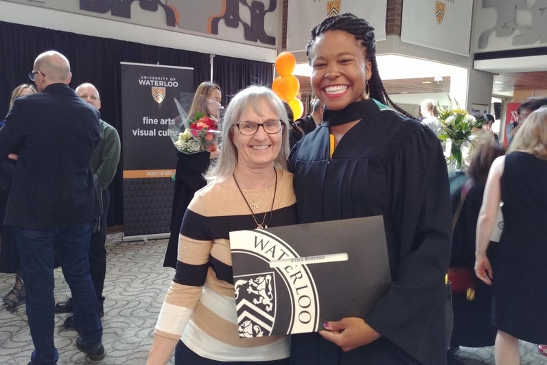 Two women standing beside each other smiling, one holding a diploma