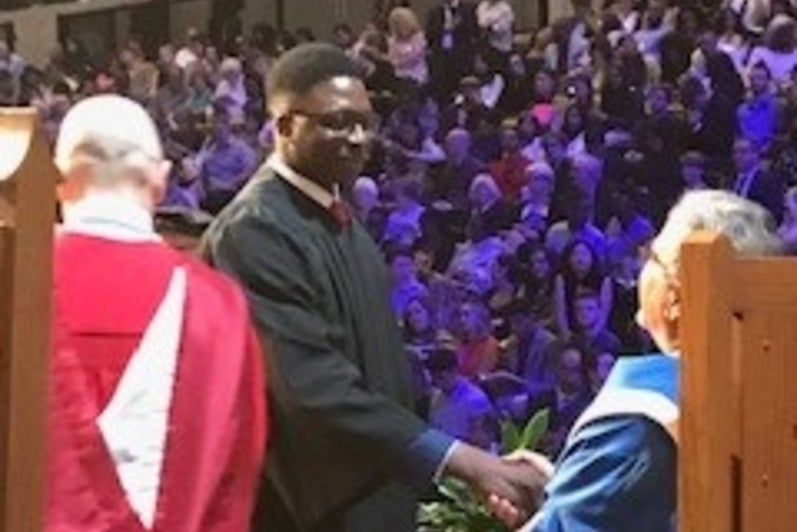 University president shaking hands with student