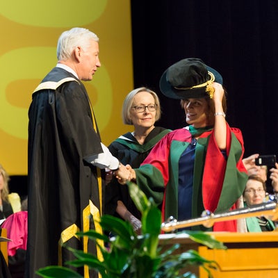 Student shaking hands and receiving PhD student hat