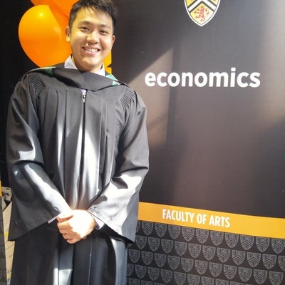 An ECON graduate beside the ECON banner