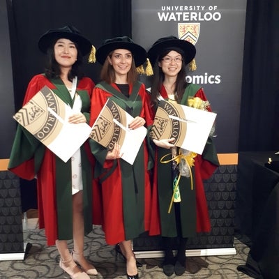 Three PhD graduates holding their degrees
