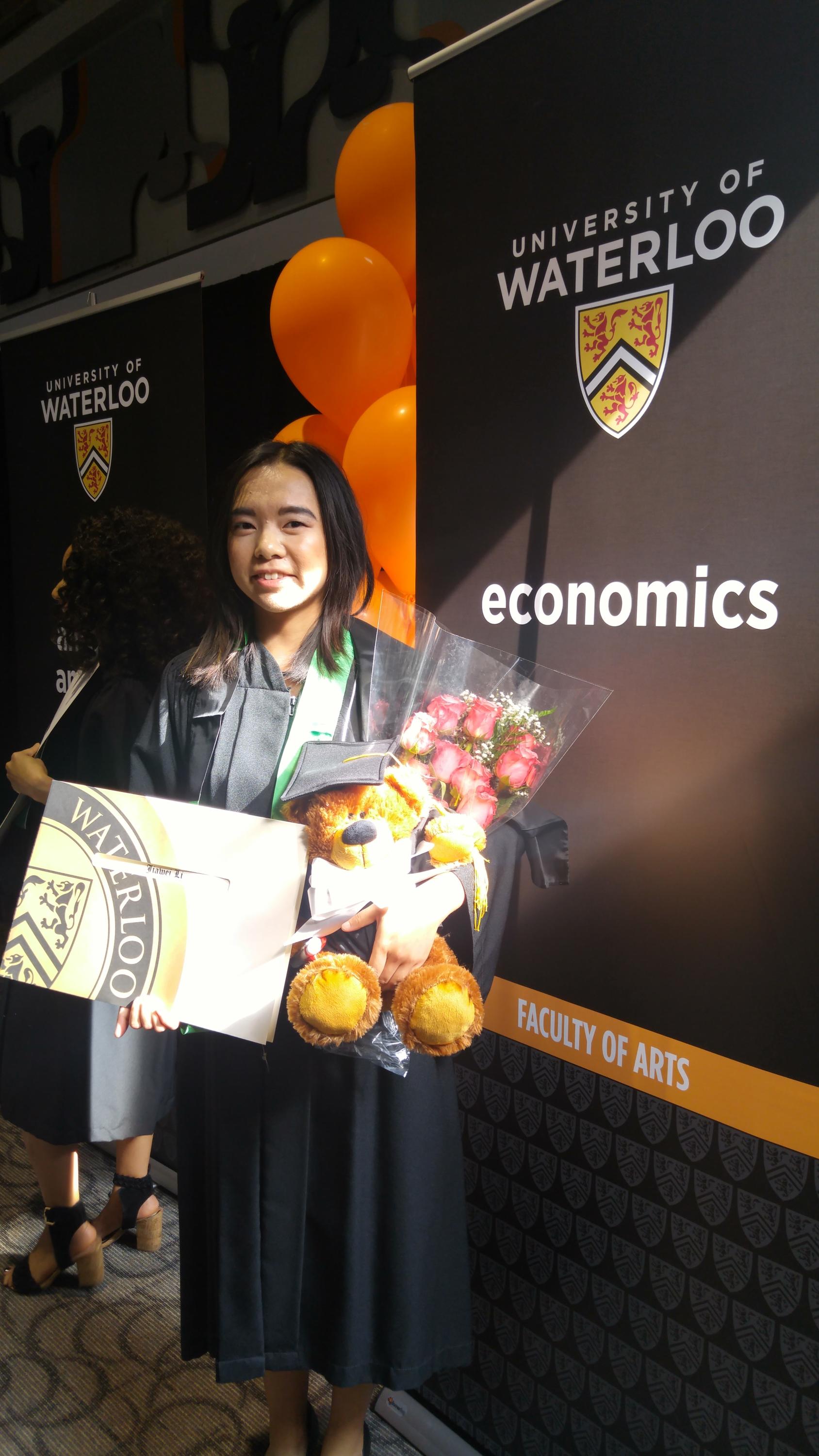 An ECON graduate beside ECON banner.