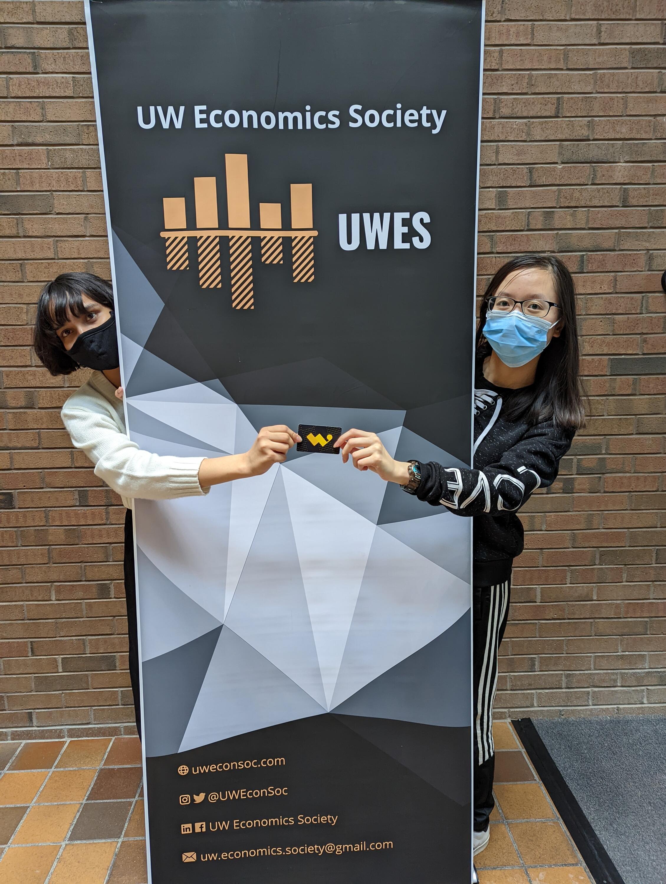 Our Student Outreach Coordinator for Fall 2021, Yana Tiwari, presents Vicky Chen with a W Store gift card in recognition of her enthusiastic participation as a mentor to 2A Economics students