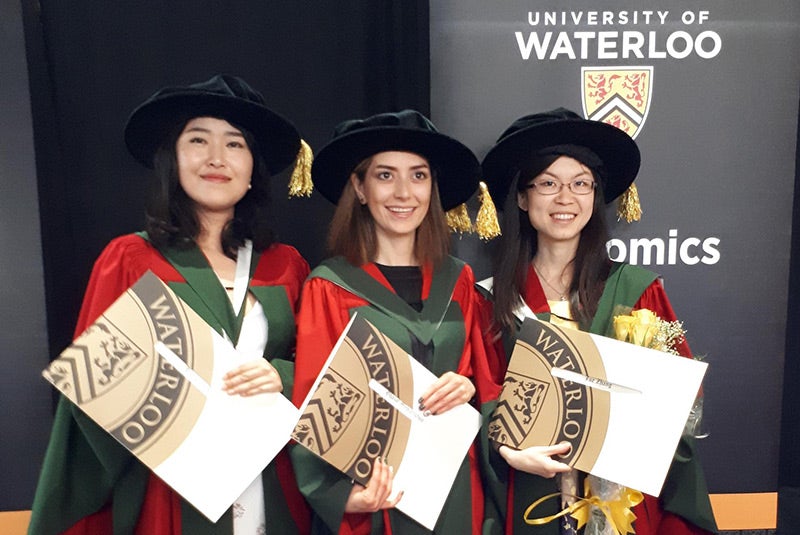 Three Economics PhDs with their diplomas