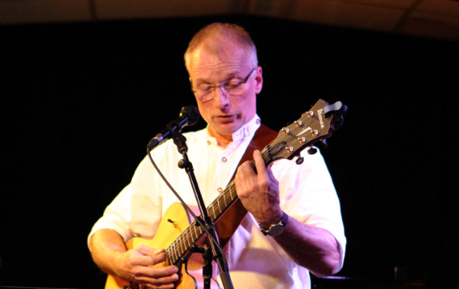 Lutz performing on stage with his guitar