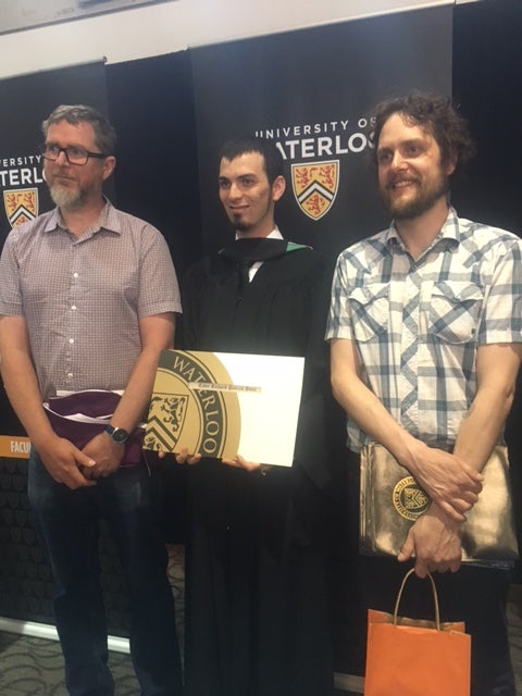 Professors Phil Curry and Jean Guillaume Forand congratulate Tyler