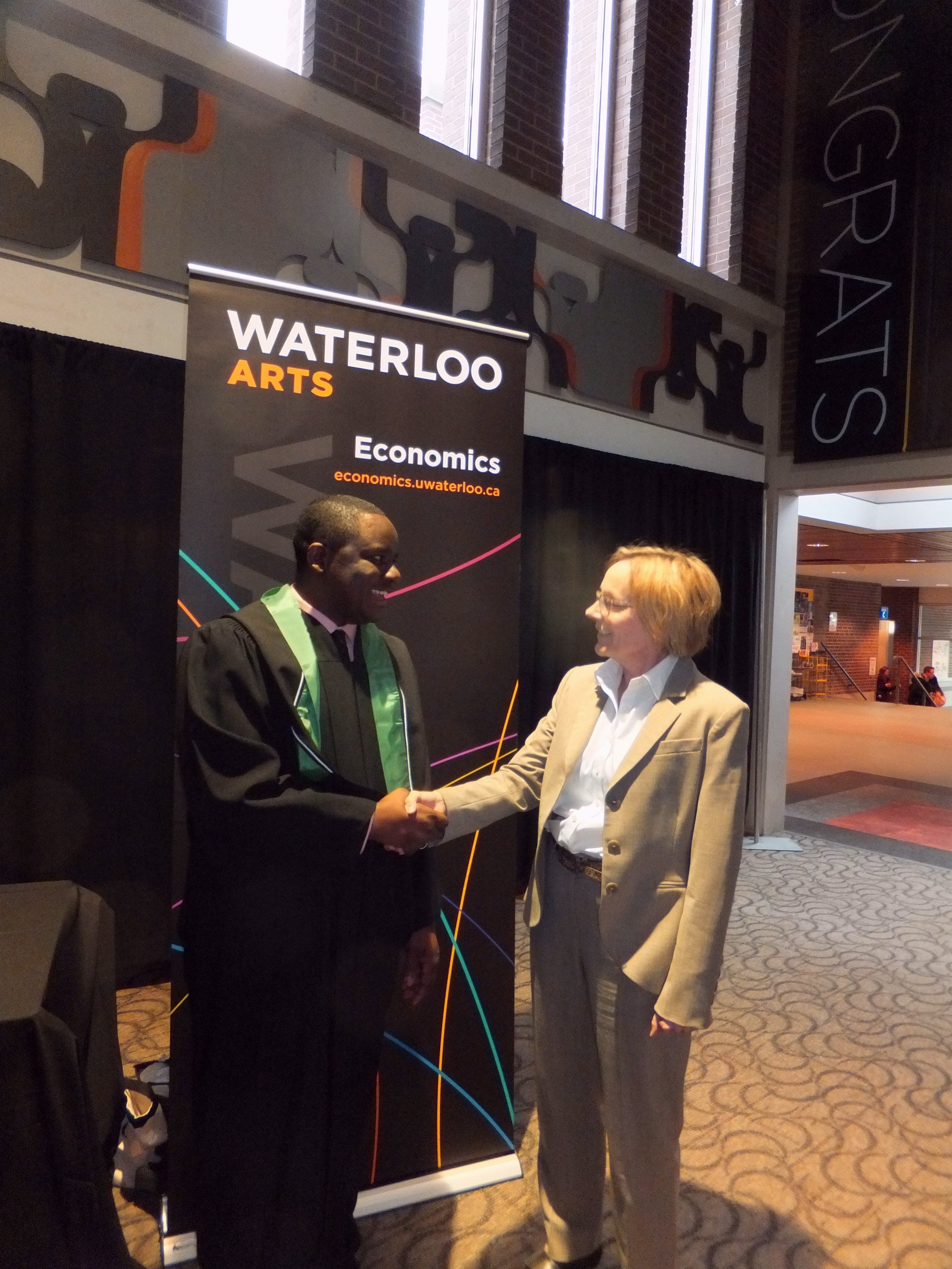 Margaret Insley shaking hands with recent economics graduate