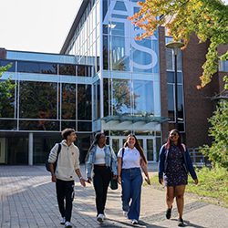four students walking away from the arts building on a Fall day