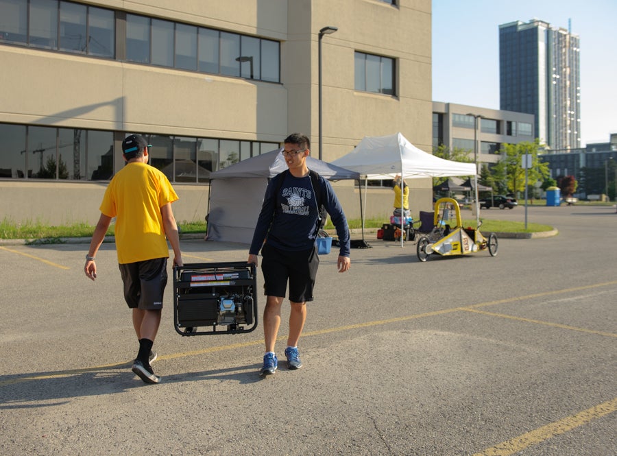 Two team members carrying a generator