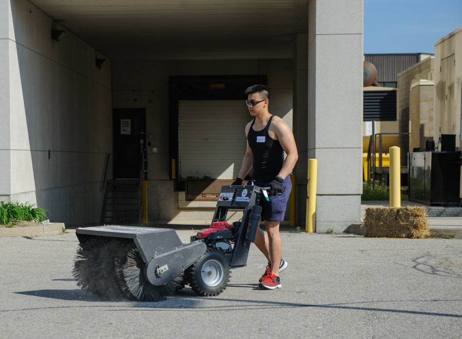 Volunteer using a sweeper to clear the track