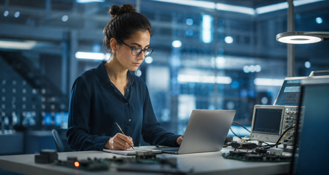 AI-generated image of an electrical and computer engineering researcher working at a laptop in a modern electronics laboratory.