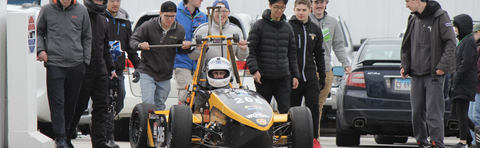 Formula Electric Team gathered outside test driving a kart