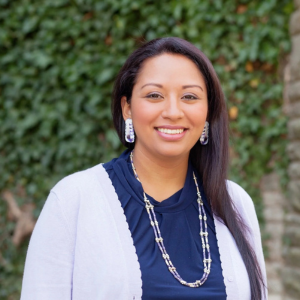 Dr. Kelsey Leonard standing infront of an ivy-covered wall.