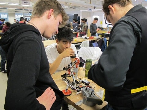 Students working with a tutor on their robotic arm.