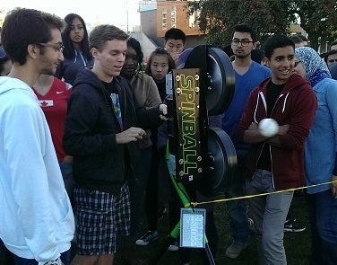 Students watch as the pitching machine works its job
