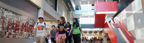 A group of campers and two leaders walking in an atrium with staircase behind them